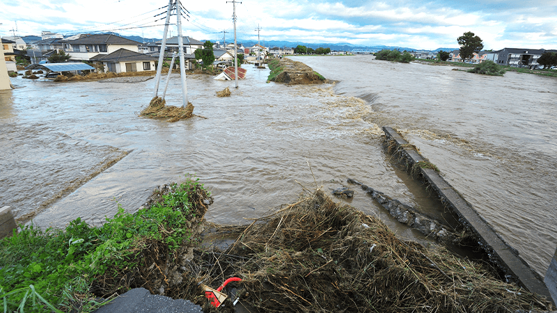 川が氾濫し、堤防が決壊して住宅街に濁流が流れ込むイメージの写真